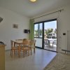 Una sala con cucina aperta, tavolo da pranzo, divano e una finestra che dà su un balcone.