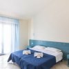 Camera moderna con letto matrimoniale, copriletto blu e tende azzurre.