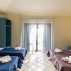 Camera spaziosa con tre letti, copriletti blu e marroni, e tendaggi chiari.