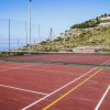 Un campo da tennis rosso con reti, situato su una collina con vista panoramica.