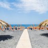 Spiaggia con sedie a sdraio e ombrelloni di paglia, fronte mare.