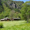 Una baita tra i prati in fiore ai piedi di montagne rocciose.