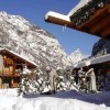 Chalet innevati circondati da montagne, cielo blu e neve abbondante.