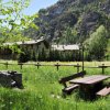 Tavolo da picnic in un prato con montagna e case sullo sfondo.