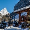 Uno chalet in legno tra neve e montagne.