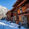 Chalet in pietra e legno circondato da neve e montagne.