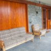 Divano e poltrona in legno su veranda con pareti di pietra.