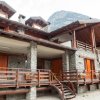 Edificio in pietra con balconi in legno e montagna sullo sfondo.