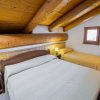 Camera con letto matrimoniale e singolo sotto travi in legno.