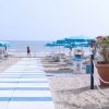 Spiaggia con ombrelloni blu e sentiero bianco.