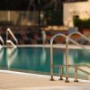Una piscina con scale metalliche e lettini sul bordo.