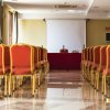 Sala conferenze vuota con sedie rosse e schermo bianco.