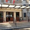 Entrata di un edificio con gradini, sedie esterne e due bandiere sopra.