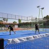 Campo da padel con superficie blu e due persone che giocano.