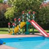 Uno scivolo colorato vicino a una piscina in un giardino alberato.