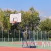 Un campo da basket all'aperto con un canestro e sedie di plastica bianche accanto.
