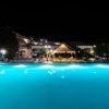Una piscina illuminata di notte con strutture alberghiere sullo sfondo.