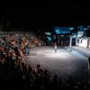 Un anfiteatro pieno di persone che assistono a uno spettacolo notturno.