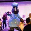 Una mascotte rinoceronte in divisa da chef balla con bambini sul palco.