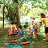 Bambini giocano su una giostra con l'aiuto di un adulto in un parco verde.