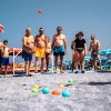 Gruppo di persone in costume da bagno gioca a bocce sulla spiaggia.