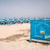 Spiaggia con ombrelloni blu e un cartello che dice 