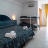 Camera d'albergo con letto matrimoniale, letto a castello e tende gialle.