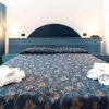 Letto matrimoniale con copriletto blu ornato e asciugamani piegati.