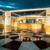 Ampia hall con pavimento decorato a raggi, bancone reception, divani, soffitto blu e colonne beige.