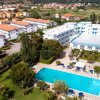 Veduta dall'alto di un complesso turistico con piscina e campi da tennis.