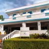 Edificio bianco con dettagli blu e un cartello di benvenuto vicino a piante e scale.