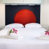 Letto matrimoniale con testiera rossa e fiori su asciugamani.