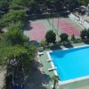 Piscina scoperta accanto a campi sportivi immersi nel verde.