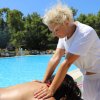 Persona riceve un massaggio a bordo piscina da un'altra persona.