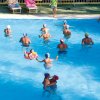 Persone che nuotano in piscina con palline colorate, un istruttore sulla riva.