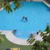 Una grande piscina all'aperto con alcuni nuotatori e alberi che circondano l'area.