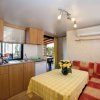 Cucina e soggiorno con tavolo a quadri gialli, divano arancione e cucinino in legno chiaro.