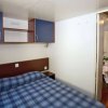 Camera con letto matrimoniale e copriletto a quadri blu e bianchi, armadi blu sopra il letto.