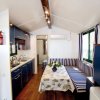 Cucina e area pranzo con mobili blu, divano a righe, tavolo con tovaglia a fiori.