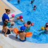 Istruttrice insegna nuoto a bambini con braccioli in piscina.