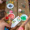 Bambini a un tavolo dipingono con colori vivaci su carta e piatti di plastica.