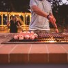 Persona che griglia cibo all'aperto su un barbecue al tramonto.
