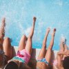 Cinque ragazzi seduti sul bordo della piscina, con i piedi immersi nell'acqua.