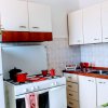 Cucina moderna con mobili bianchi e marroni, fornello a gas e pentole rosse.