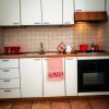Cucina con mobili bianchi, piano in legno chiaro, stoviglie rosse e forno nero.