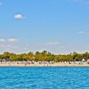Spiaggia con alberi sullo sfondo e cielo sereno.