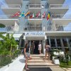 Facciata di un hotel con persone davanti e bandiere sul balcone.