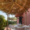 Patio con tavolo e sedie sotto un tetto di paglia.