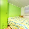 Una camera da letto con pareti verdi, un armadio e un letto con copriletto a righe colorate.