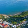 Vista aerea di un resort con piscina, spiaggia e mare turchese circondato da vegetazione.